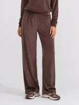 Pantalón de corte recto confeccionado en tejido plush con acabado aterciopelado. Presenta cintura elástica, bolsillos laterales y un bolsillo trasero, ofreciendo una caída fluida y cómoda.