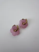 Aros de acero quirúrgico dorados en forma de argolla con dije colgante de flor en resina color rosado.