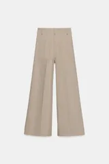 Jeans de tiro alto con corte wide leg y largo al tobillo. Presentan costuras verticales marcadas en el frente, cintura con trabillas y cierre frontal con cremallera, botón y gancho metálico.