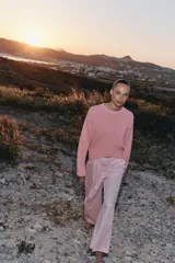 Sweater de punto color rosado con cuello redondo y manga larga, de bajo asimétrico con acabados en rib.