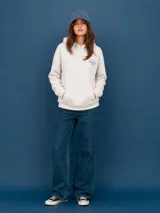 Buzo con capucha color off-white, de corte holgado, con bolsillo frontal tipo canguro y estampado pequeño en el pecho con la frase 'Tierra de Campeones' y cuatro estrellas en color azul.