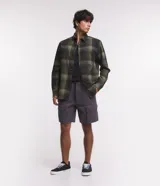 Camisa de franela a cuadros en tonos de azul marino y gris oscuro, con corte regular, manga larga, cuello camisero, cierre frontal de botones y un bolsillo en el pecho.