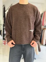 Sweater de punto liviano marrón melange, con cuello redondo y diseño relaxed, mangas largas y pequeño estampado en el lateral inferior.