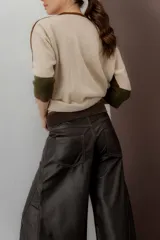 Pantalón de cuero ovino italiano de tiro medio y corte ancho. Presenta costuras diagonales en las piernas que aportan volumen y vuelo, con pretina y pasacintos confeccionados en gamuza al tono.