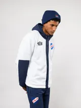 Campera de polar blanca con capucha y detalles en azul marino, con cierre frontal completo. Presenta el logo de Umbro y el escudo del Club Nacional de Football en el pecho.