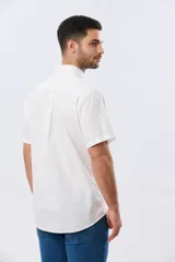 Camisa de manga corta confeccionada en mezcla de lino y algodón, color beige, con cuello camisero abotonado, bolsillo frontal en el pecho y cierre de botones.