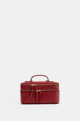 Bolso tipo vanity de diseño estructurado, color rojo, con doble compartimento y cierre de cremallera. Cuenta con asa de mano superior y correa bandolera extraíble y ajustable.
