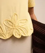 Blusa amarilla de mangas cortas con cuello redondo y bajo con flores bordadas.