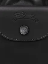 Cartera tipo bucket pequeña de cuero negro, con cierre de cordón ajustable y solapa frontal con botón a presión. Incluye correa larga ajustable para llevar cruzada.