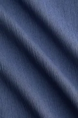 Top sin mangas de punto elástico texturizado en color azul, con escote bote y frunces en los laterales que crean un efecto drapeado.