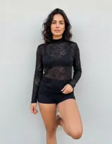 Polera de encaje negro transparente con cuello alto y mangas largas, modelo Lumiere.