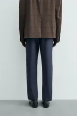 Pantalón chino de corte regular fit, confeccionado en tejido de algodón con elasticidad. Presenta bolsillos frontales, bolsillos traseros de vivo y cierre frontal con cremallera y botón.