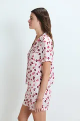Pijama de dos piezas compuesto por una camisa de manga corta con botones frontales y un short, ambos con estampado de labios en tonos rosados y rojos.