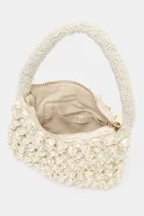 Bolso de mano pequeño con diseño estructurado, completamente cubierto de abalorios perlados. Cuenta con un asa superior también decorada con cuentas y cierre de cremallera metálica.