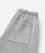 Pantalón de corte baggy confeccionado en algodón con felpa, color gris melange. Presenta cintura elástica con cordón ajustable, bolsillos laterales y bajo con regulador elástico.