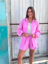 Conjunto de dos piezas confeccionado en lino color blanco. Incluye una camisa de corte holgado con mangas abullonadas y bolsillos frontales, y un short de tiro alto con cintura elástica y forro interior.