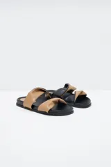 Sandalias planas con base negra y dos tiras anchas superiores, una color beige y otra negra, con efecto arrugado.