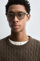 Jersey de punto color marrón oscuro, con cuello redondo y manga larga. Presenta un tejido con estructura de ochos y acabados en rib.