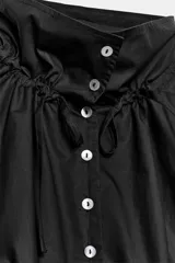 Cazadora de algodón negra con cuello subido ajustable con lazadas, manga larga, bolsillos de vivo en los laterales y bajo ajustable con cordones. Cierre frontal con botones.
