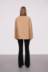 Campera color beige con cuello marrón de cuero sintético, cierre con botones a presión, cuatro bolsillos frontales y puños con botón.