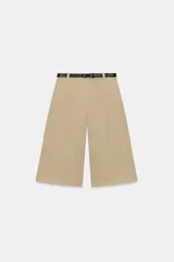 Bermuda larga de tiro medio color beige, con bolsillos en el delantero, pinzas y cierre frontal con cremallera y ganchos metálicos. Incluye cinturón fino de cuero sintético negro con hebilla metálica.