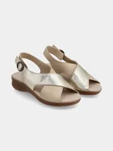 Sandalia de cuero con diseño de tiras cruzadas en combinación de tonos metalizado dorado y beige, con cierre de hebilla lateral y suela de goma tipo corcho.