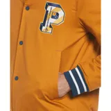 Campera estilo universitario color mostaza, con cierre de botones a presión, bolsillos laterales y un bolsillo interno. Tiene un parche con la letra P en el pecho y ribetes a rayas en puños y cintura.