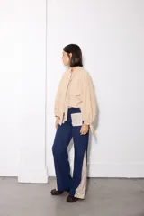 Camisa de tela afelpada color beige con nudo en el cuello, mangas abullonadas con lazos en los puños y bolsillos frontales con tapa.