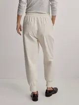 Pantalón jogger de sarga color beige, con cintura elástica ajustable con cordón y puños elásticos en los tobillos.