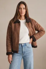 Campera tipo gamulán de corte oversize, color marrón con interior y cuello de corderito sintético oscuro. Presenta cierre frontal, detalles de costuras reforzadas y terminaciones en puños y ruedo con corderito a la vista.