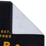 Toalla de playa negra con estampado en color dorado que incluye el logo de Rip Curl, un canguro y la frase "Road Trippin' Down Under".