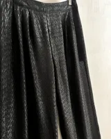 Pantalones negros de pierna ancha con diseño geométrico en lúrex plateado. Tiro medio con detalle de tableados en el frente.