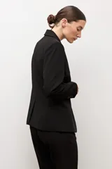 Blazer clásico color negro de corte entallado, con solapa de muesca, cierre de un botón frontal y bolsillos de ojal en los laterales.