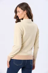 Buzo tejido combinado de color beige, con cuello alto, medio cierre metálico y puños y ruedo acanalados en tono tostado.