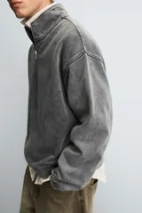 Sudadera de corte boxy fit con cuello subido y cierre frontal de cremallera. Presenta mangas largas, acabado efecto lavado y puños y ruedo en rib.