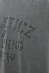 Camiseta de corte regular fit confeccionada en algodón, con cuello redondo y manga corta. Presenta un estampado frontal con el texto 'ATHLETICZ TRAINING CREW' con efecto desgastado.