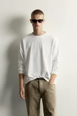 Camiseta relaxed fit de manga larga color blanco, confeccionada en tejido de modal y algodón fluido, con cuello redondo y puños de rib.
