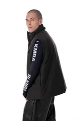 Chaleco negro con estampado de logos, cuello alto, cierre frontal con cremallera y broches a presión ocultos, bolsillos delanteros y cintura ajustable con cordón elástico. Interior de tafeta relleno de guata.