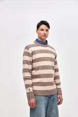 Buzo de punto con diseño de rayas horizontales en azul marino y beige, cuello redondo y puños acanalados. Presenta un pequeño bordado de estrella en la manga.