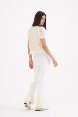Pantalon tejido de corte recto y tiro alto, color blanco, con detalle de encaje y perlas en el ruedo.