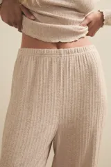 Pantalon de tejido de punto acanalado en color beige, con corte recto y holgado, y terminaciones con borde ondulado en el ruedo.