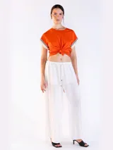 Remera color naranja de manga corta, confeccionada en algodón, con detalles de flecos y bordado en las mangas.