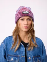 Gorro tipo beanie de tejido acanalado con diseño a rayas verticales en tonos azul y bordó. Presenta un parche ovalado con el logo de la marca Rusty en el frente.
