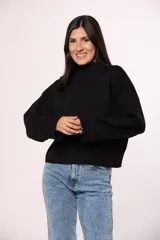 Buzo tejido de punto color negro, con cuello redondo, mangas largas con puños acanalados y corte holgado.