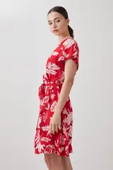 Vestido corto cruzado de color rojo con estampa floral blanca, con volados en el ruedo y lazo para ajustar en la cintura.