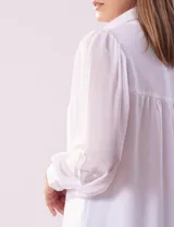 Camisa blanca de gasa marca Tahari, con cuello con solapa y abertura central con botones ocultos. Manga larga con puño y botones.