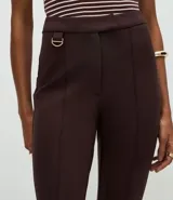 Pantalón de corte flare confeccionado en punto roma, con cintura estructurada, detalle de hebilla decorativa, cierre frontal y bolsillos posteriores.