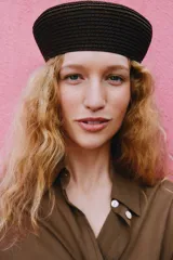 Gorro tipo casquete de diseño circular, confeccionado en tejido de punto trenzado en color marrón oscuro.