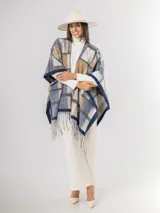 Ruana abierta con diseño de cuadros en tonos azul, beige y blanco, con terminación de flecos en el ruedo.