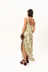 Vestido largo de tela sedosa con estampado abstracto en tonos verde oliva, blanco y negro. Presenta escote en V profundo, tirantes anchos y tajos laterales pronunciados en la falda.